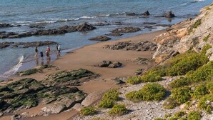 A rocky beach with clear water, a few people, and distant city skyline. - Spacious mobile home 6 people, terrace (Saint-Michel-Chef-Chef)