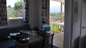A dining area with a table set for four, a bench, and a view of the outdoors.