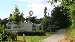 A campsite with RVs parked on a gravel path, surrounded by greenery and trees. - Cozy chalet with terrace in Naucelle - Idyllic location (Naucelle)