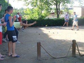 A group of people playing a game outdoors with a rope barrier and a dirt ground.