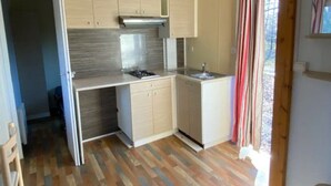 A compact kitchen with a gas stove, a sink, and wooden cabinets.