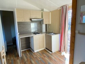 A compact kitchen with a gas stove, a sink, and wooden cabinets.