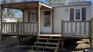 A small, single-story mobile home with a porch and a small deck.