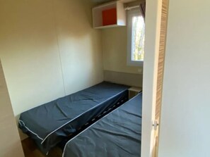 A small, single-bed room with a window and a door.