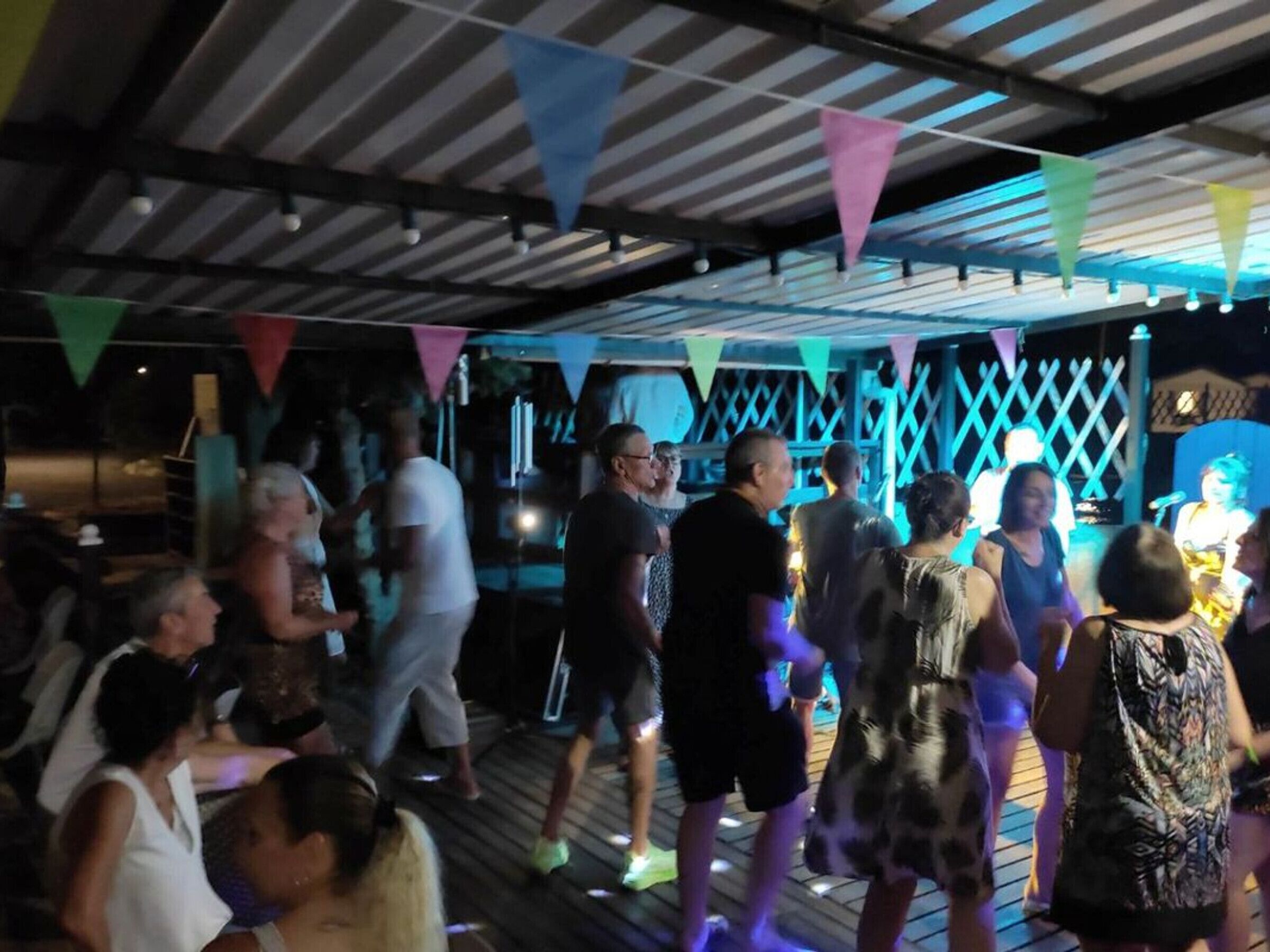 A crowded indoor venue with a wooden deck and a lattice structure in the background.