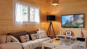 Ein gemütliches Wohnzimmer mit einer Couch, einem Couchtisch, einem Fernseher und einer Lampe.