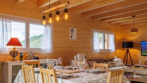 Ein gemütliches Holzhaus-Interieur mit Essbereich, einer Couch und einem Fernseher.