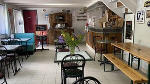 A café with tables and chairs, a counter, and a staircase. - Mobile Home with Terrace in Guégon (Guégon)