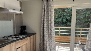 A modern kitchen with a gas stove, wooden cabinets, and a coffee maker. - Mobile Home with Terrace in Guégon (Guégon)