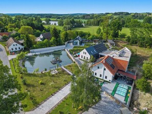 A residential area with houses, a pond, and a solar panel-equipped building. - Wonderful private villa for 8 guests with WIFI, private pool, hot tub, TV, terrace and pets allo... (Prostý)
