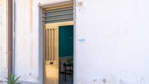 A door with a number plate, a potted plant, and a glimpse of a room with a green wall and a sofa. - Apartment 'Ciuri' with Wi-Fi and Air Conditioning (Avola)