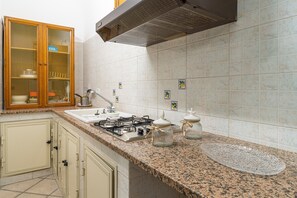 A kitchen with a gas stove, sink, wooden cabinets, and a tiled backsplash.
