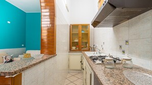 A kitchen with a granite countertop, a stove, a sink, and a wooden cabinet. - Apartment 'Ciuri' with Wi-Fi and Air Conditioning (Avola)