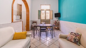 A room with a dining table, chairs, a sofa, a TV, and a window. - Apartment 'Ciuri' with Wi-Fi and Air Conditioning (Avola)