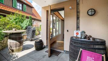 A wooden barrel, a table, and chairs outside a building with a door open.