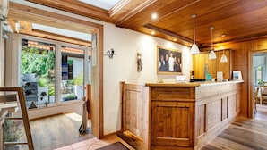 Interior de madera con mostrador de cocina, techo de madera y vista a través de un ventanal.