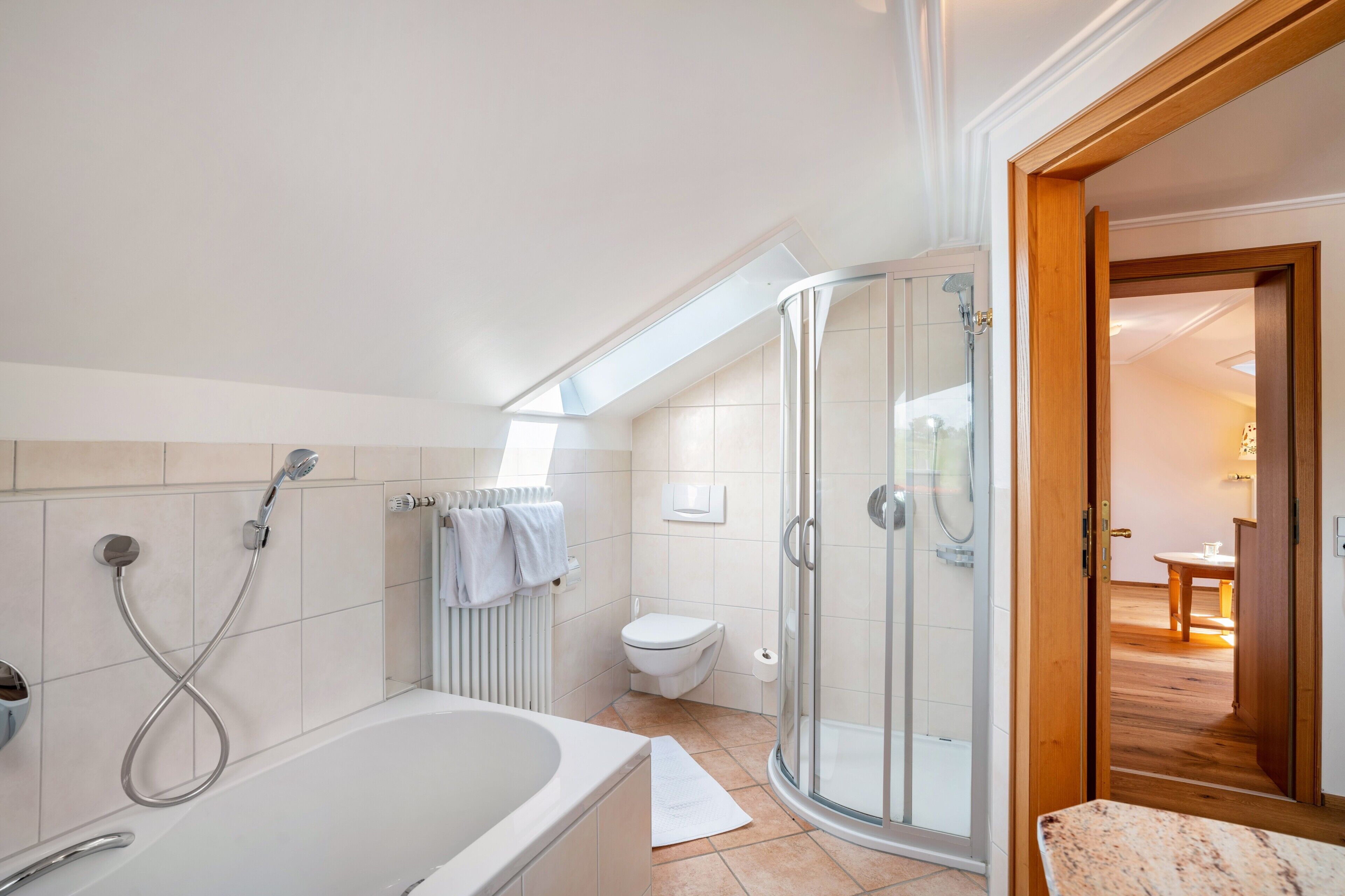 Une salle de bain moderne équipée d’une baignoire, d’une douche, de toilettes et d’un espace douche séparé par des parois en verre.