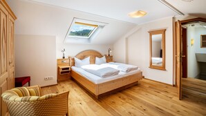 A bedroom with a wooden bed, a skylight, a bedside table with a lamp, and a mirror on the wall. - Country House Room 'Dachjuche' with Mountain View and Wi-Fi (Bühlertal)