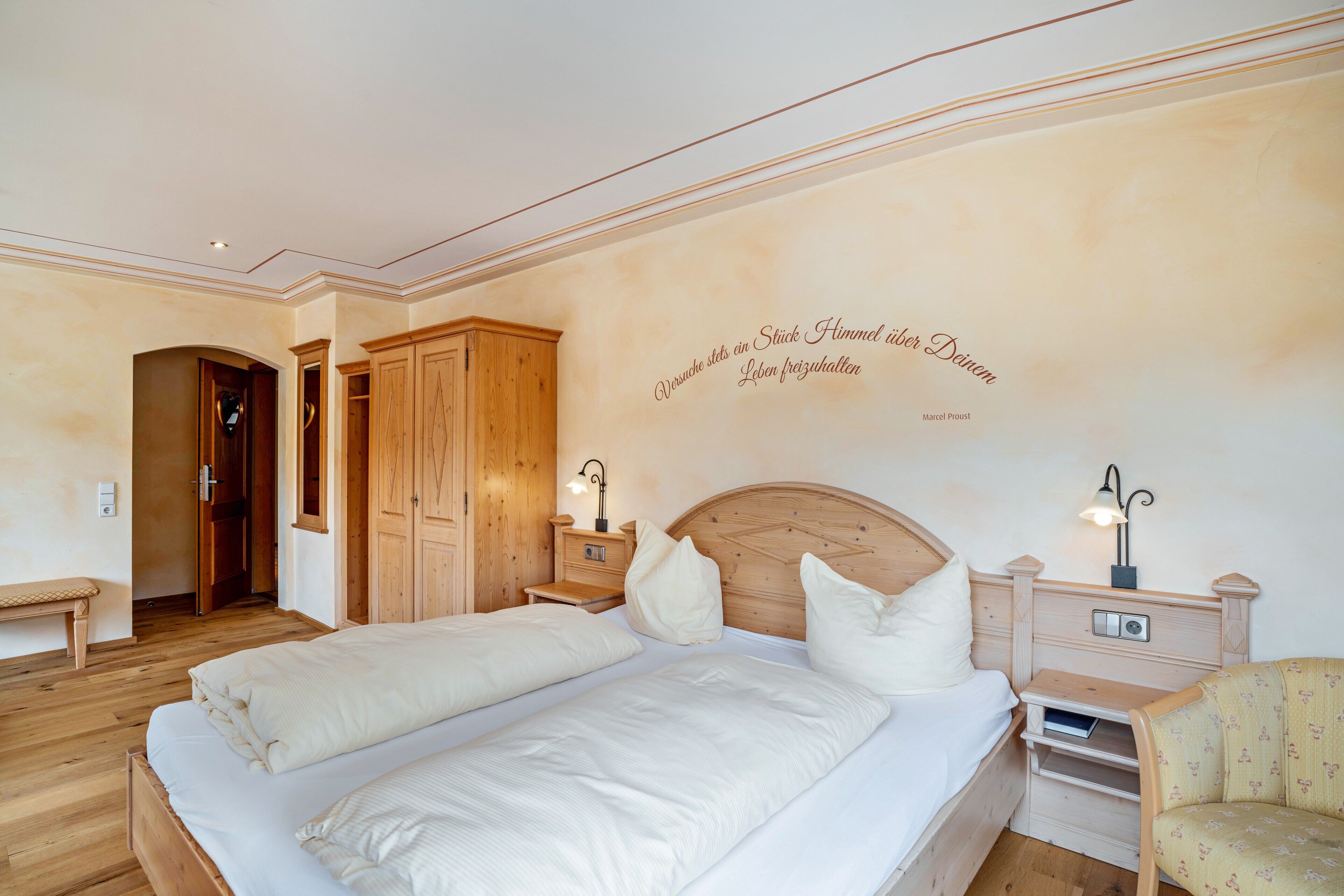 Ein Schlafzimmer mit zwei Betten, einem Holzschrank, Nachttischen mit Lampen und einer Wanddekoration.
