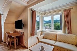 A room with a wooden dining table, a sofa, a TV, and a window with curtains.