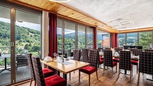 A restaurant with a large table and chairs, large windows with a view of a forested area, and a wooden ceiling. - Country House Room 'Lebensfreude' with Mountain View and Wi-Fi (Bühlertal)