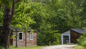 Eine rustikale Holzhütte mit einem Kiesweg, umgeben von dichtem Wald.