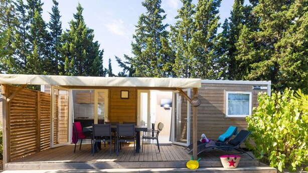 Una cabaña de madera con un porche cubierto, un comedor y una sala de estar con piscina.
