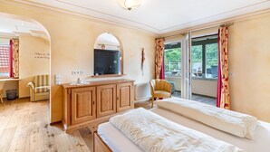 Habitación de hotel con una cama, un armario de madera, un televisor, una silla y vistas al exterior.