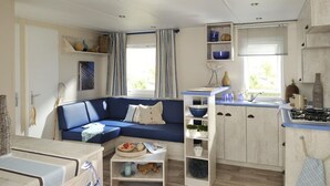 Un espace de vie compact comprenant un canapé, une kitchenette et un coin repas.