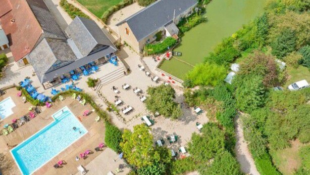 Vue aérienne d’un hôtel doté d’une piscine, d’un espace de détente extérieur et situé au bord d’une rivière.