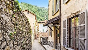 A narrow cobblestone street flanked by historic buildings with stone walls and traditional shutters. - Nice apartment for 4 guests with WIFI, balcony and pets allowed (Argegno)