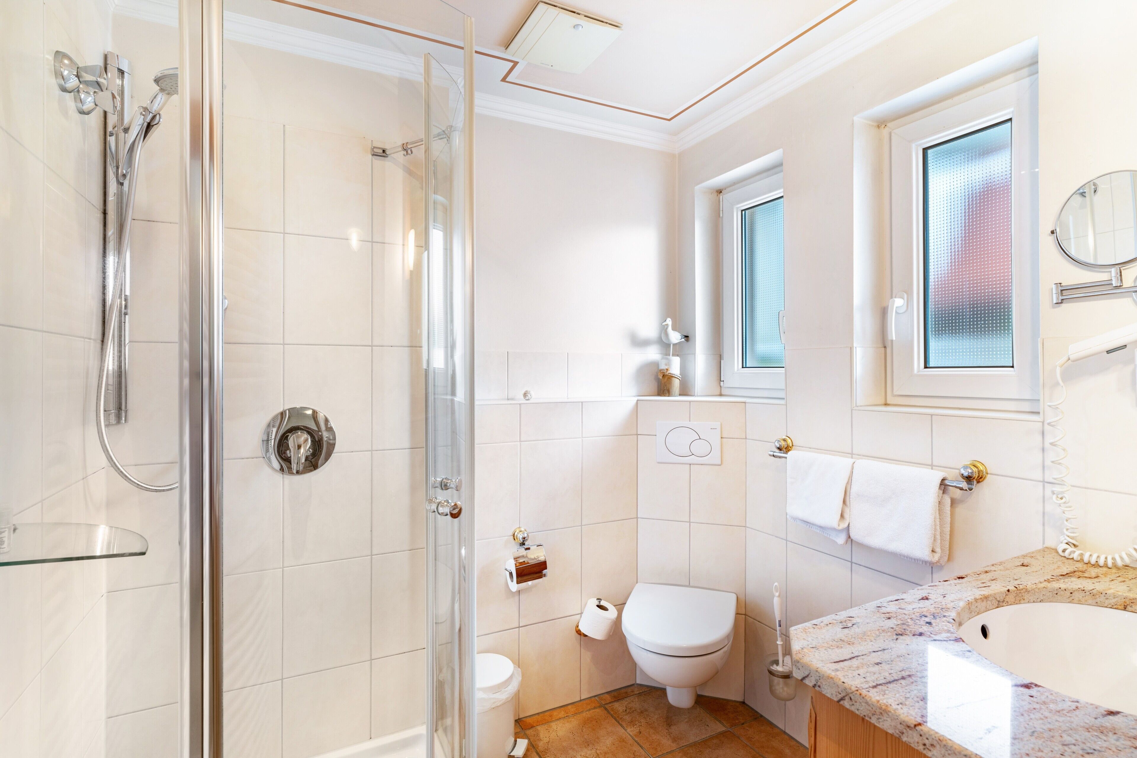 A bathroom with a shower, toilet, sink, and a window with a view.