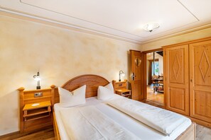 Ein Schlafzimmer mit zwei Betten, Holz-Kopfteilen, Nachttischen mit Lampen und einem Kleiderschrank.
