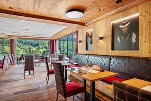 Ein Restaurant mit Holzbalkendecken, großen Fenstern und Blick auf Grünflächen.