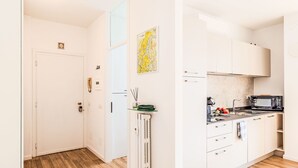Eine moderne Küche mit weißen Schränken, einer Mikrowelle und einer kleinen Kochinsel mit einem grünen Handtuch.