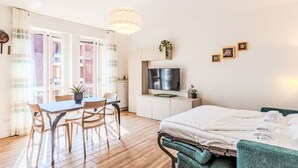 Ein modernes Zimmer mit einem Bett, einem Fernseher, einem Esstisch und Stühlen.