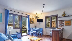 Una sala de estar acogedora con un sofá, una mesa de comedor con sillas, un televisor y una cocina con un radiador.