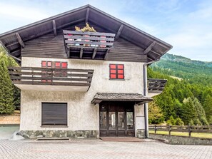 A modern house with a stone facade, a balcony, and a mountain view.