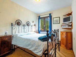 A bedroom with a bed, wooden nightstand, dresser, and a window with curtains.