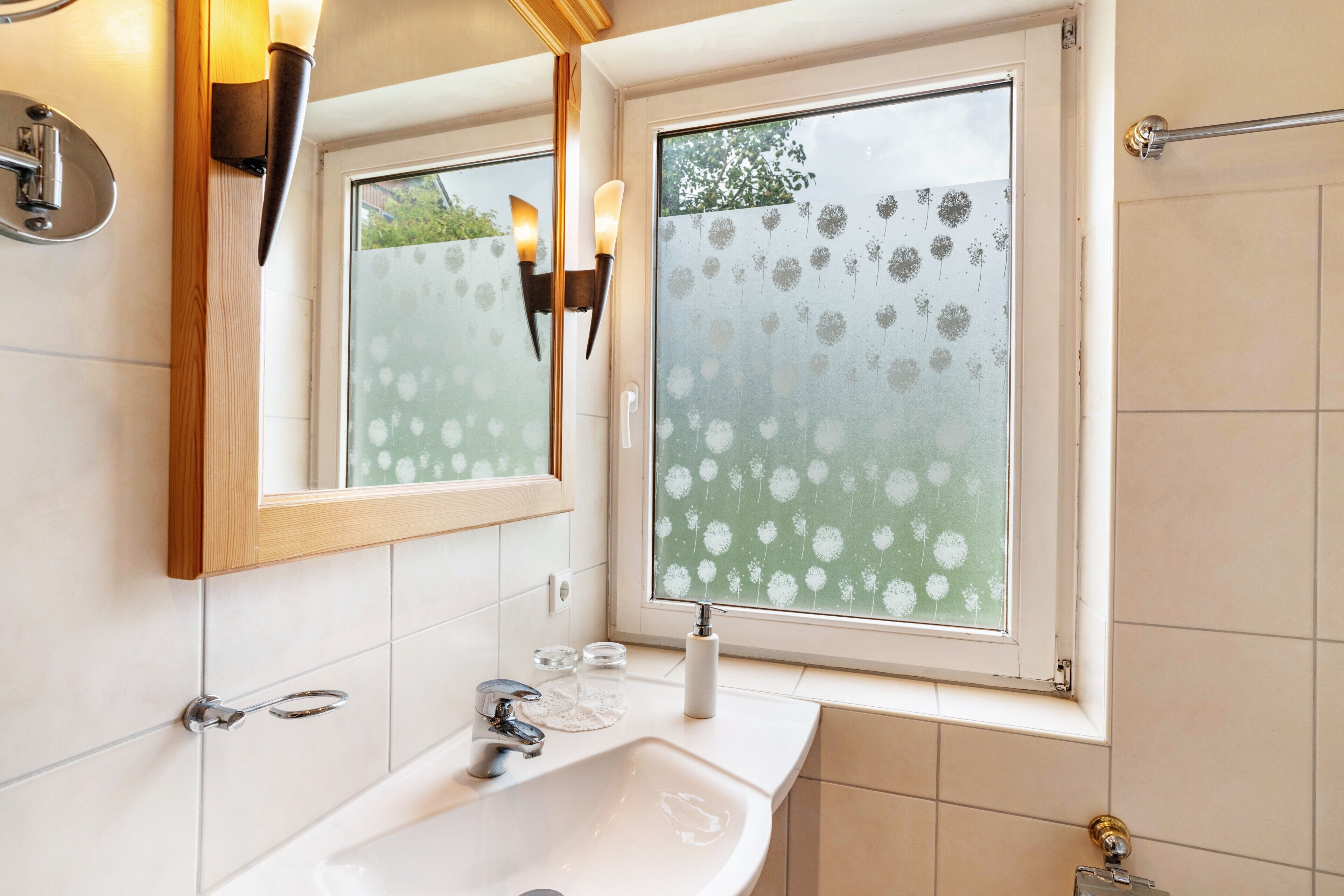 Een badkamer met een groot raam, een spiegel, een wastafel en een handdoekhouder.