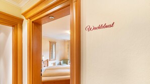 A hotel room with a wooden door frame, a bed, a nightstand, and a mirror.