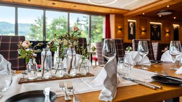 Une table à manger dressée avec de la vaisselle, des assiettes et des couverts, et offrant une vue sur la verdure environnante.