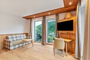 Una habitación moderna con techo de madera, un sofá, una mesa, una silla y un televisor montado en una pared de madera.