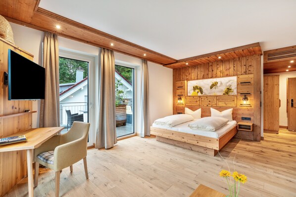 Une chambre avec un plafond en bois, un lit, un bureau avec une chaise et un téléviseur.