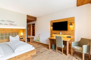 Una habitación de madera con una cama, un escritorio y un televisor montado en la pared.
