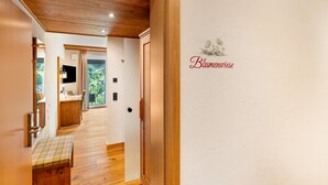 A hallway with wooden flooring, a bench, a door, and a wall with a floral design and text. - Nature Room 'Flower Meadow' with Balcony, Wi-Fi and Air Conditioning (Bühlertal)