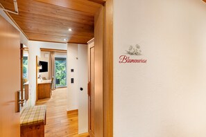 A hallway with wooden flooring, a bench, a door, and a wall with a floral design and text. - Nature Room 'Flower Meadow' with Balcony, Wi-Fi and Air Conditioning (Bühlertal)