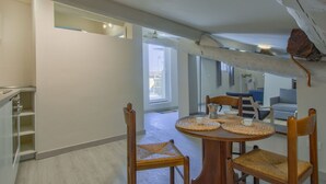 A dining area with a round table and four chairs, a kitchen area with a counter and cabinets, and a view of a balcony through an open doorway. - Nice apartment for 2 people with WIFI, A/C, TV, terrace and pets allowed (Pisa)
