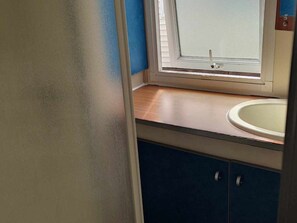 A bathroom with a window, a sink, and cabinets. - Mobile home with terrace for 6 people in Anduze (Anduze)