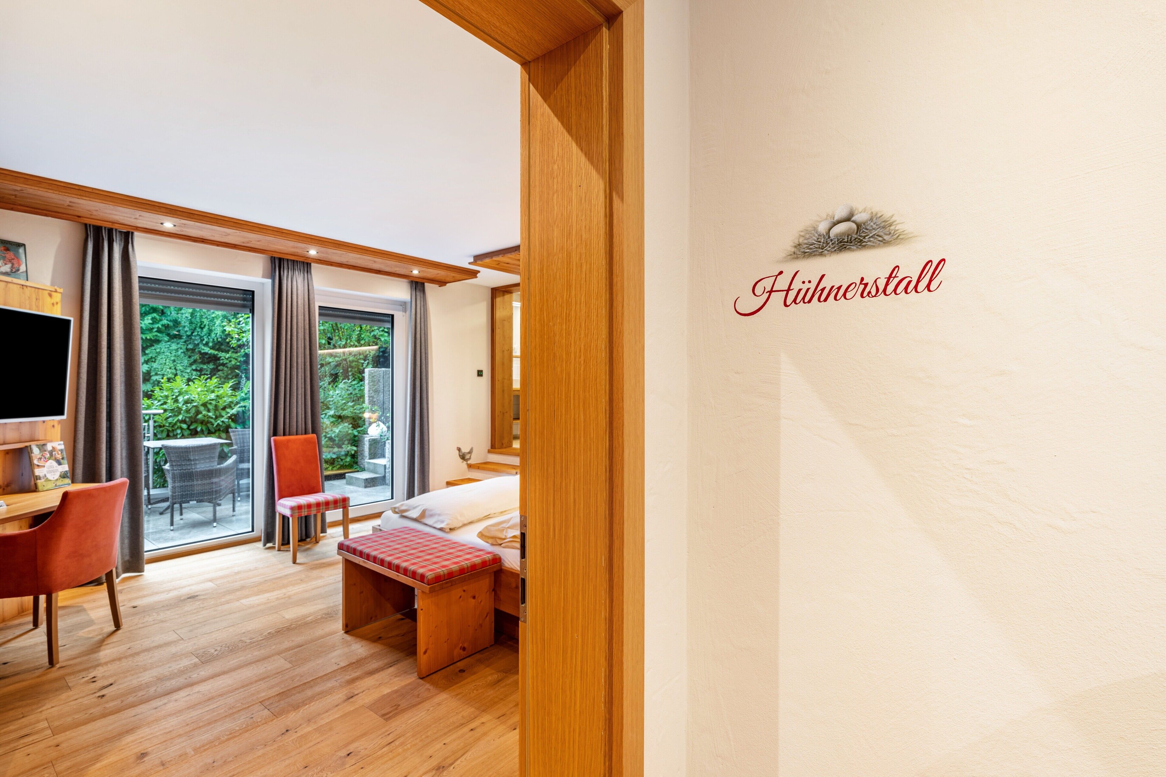 Ein Hotelzimmer mit Bett, Schreibtisch, Stuhl, Bank und Blick ins Freie.